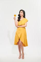 Young celebrating woman red dress . Beautiful model portrait isolated over studio background hold wine glass.