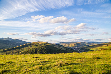 glade on a background of mountain tops and blue sky with clouds. beautiful panorama