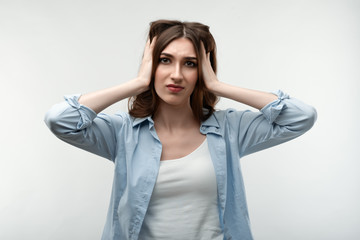 Annoyed Young woman covering ears, feeling pain, isolated on white studio background