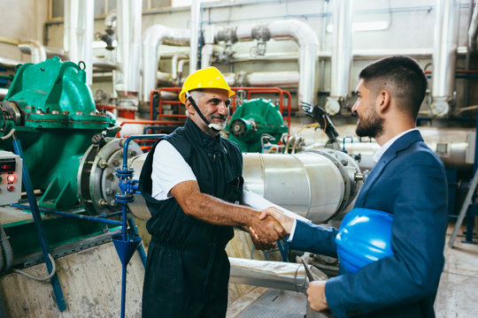 Supervisor And Blue Collar Handshake Indoor In Industry Plant