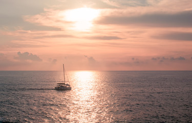 Naklejka na ściany i meble A sailboat playing in the sea at sunset