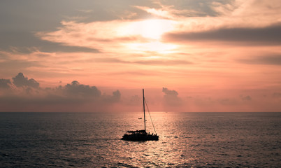 A sailboat playing in the sea at sunset