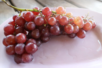 Ripe red grape on a pink plate.