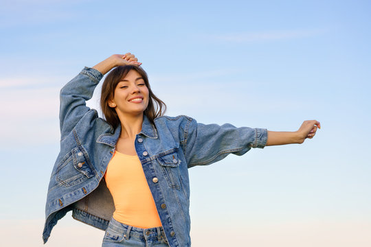 girl in denim jacket and jeans posing against the sky