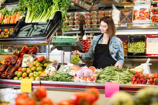 Adult woman seller weighing fruit and vegetables in grocery shop