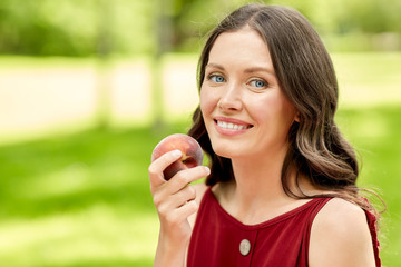 healthy eating and people concept - portrait of happy woman with peach at summer park