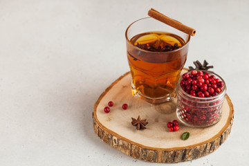 Hot tea with spices, Apple and berries in a transparent glass mug on a wooden stand. concept home comfort. Copy space