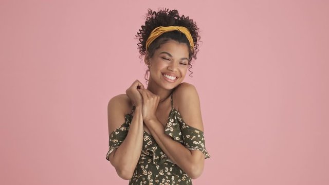 A pleased african american young woman is getting compliments standing isolated over pink background