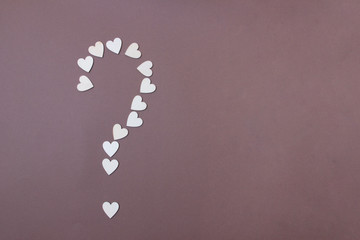 question mark lined from wooden hearts on brown background
