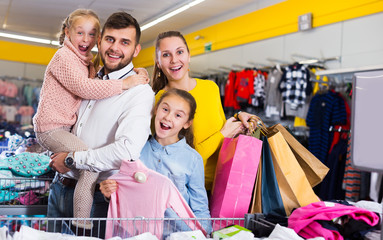 Portrait of friendly family of four with shopping bags in clothing shop