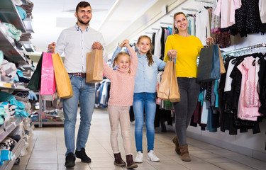 Fototapeta premium Positive family with two daughters walking in store after shopping