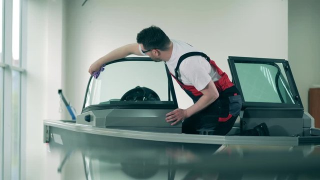 Male technician is cleaning windshield of a sailboat