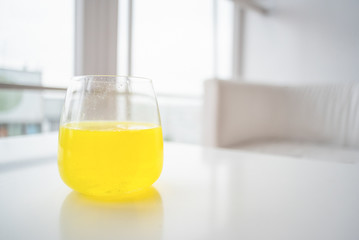 Glass with dissolved ascorbic acid in water on the white table background.