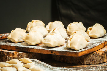 Semi-finished dumplings manti on the wooden board