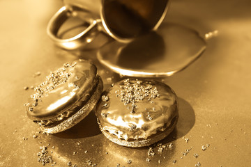Liquid gold flows from a golden cup. Golden cookies on a gold background.
