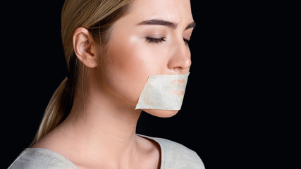 Upset woman with closed eyes and sealed mouth with tape