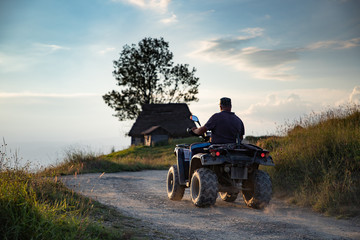 Obraz premium man on atv in mountain sunset