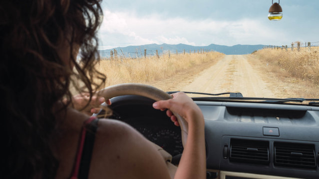 Woman Driving A Van Down A Dirt Road In The Mountains. Road Trip, Adventure