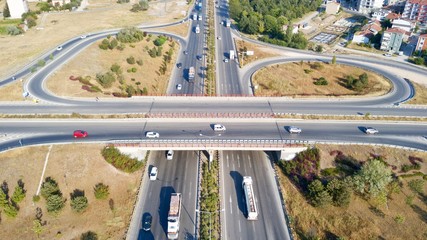Aerial view of two lane bridge driveway. There is an roundabout road at the bottom. Vehicles and commercial vehicles can also be seen.