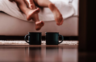 Cups of coffee and with couple behind in bed. Couple in love. Good morning. Coffee cups. 
