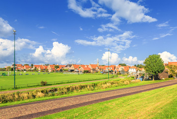 Fototapeta premium Nieuwstad, Hindeloopen, province of Friesland, municipality Súdwest-Fryslân, Netherlands, september 3, 2017: View backside of properties on Nieuwstad and Tower of the Great Church, Grutte Tsjerke