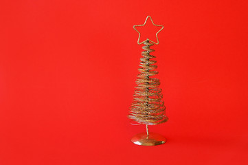 Golden metal Christmas tree with a star on top, red background.