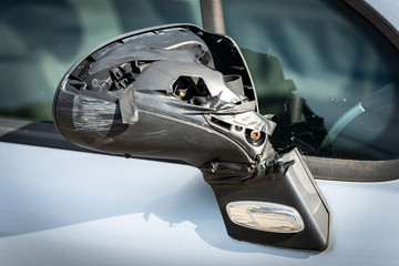 Closeup of a side broken rearview mirror of a car, fixed with tape. City road accident