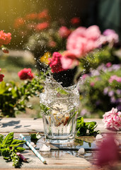 Splash of lemonade in a glass with lemonade with basil and ice cubes. Detox drink water. Outdoor shot in sunny day. Toned photo
