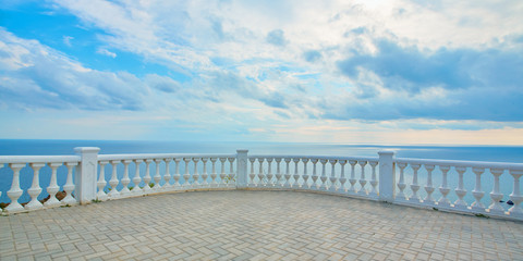 Summer time. Panoramic ocean view. Seascape. Empty promenade. Blue cloudy sky. Crystal calming sea water on horizon
