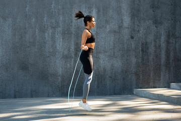 Fototapeta premium Side view of black girl exercising with skipping rope