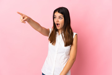 Young caucasian woman isolated on pink background pointing away