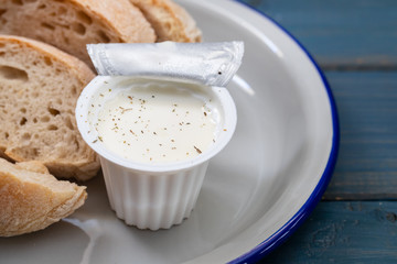 fresh cheese in plastic box and bread on blue wooden background