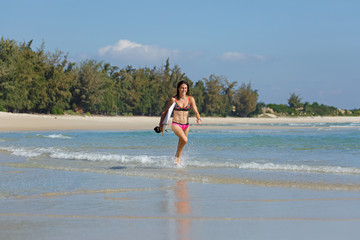 Fototapeta premium young slender and tanned girl in a swimsuit with a surfboard in her hands on the beach near the water, sea, summer, heat, sunny day, clear sea water, wave, lifestyle, sports, leisure, vacation, weeken