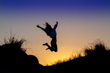 Silueta de chica saltando alegre en la puesta de sol