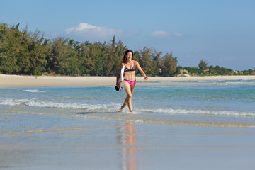 Fototapeta premium young slender and tanned girl in a swimsuit with a surfboard in her hands on the beach near the water, sea, summer, heat, sunny day, clear sea water, wave, lifestyle, sports, leisure, vacation, weeken