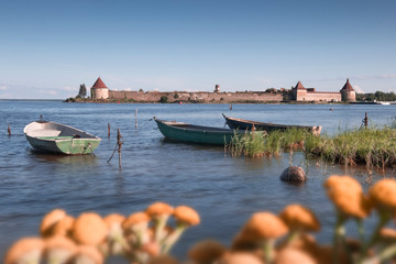  old boats on Lake Ladoga against the background of the ancient  fortress Oreshek in summer sunny day