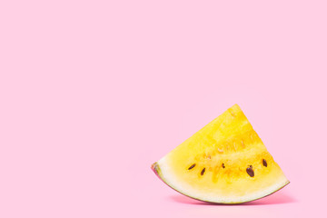 slices of yellow watermelon on a pastel pink background, copy space