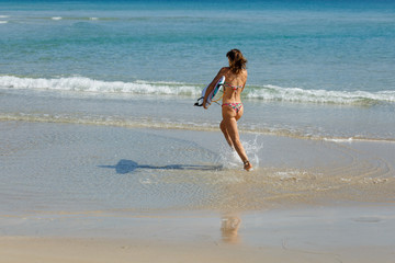 young beautiful girl in a swimsuit with a surfboard in her hands on the beach near the water, sea, summer, heat, sunny day, clear sea water, wave, lifestyle, sport, leisure, vacation, day off,