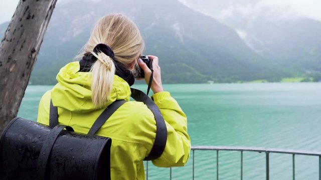 Outdoor Girl in Yellow Jacket taking Pictures of Mountain Lake View