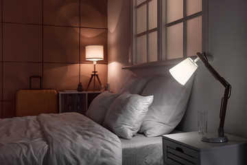 Interior of modern hotel room with glowing lamps at night