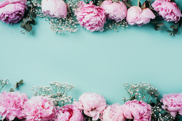 Creative frame pattern of pink peonies, gypsophila flowers, eucalyptus on blue background. Flat...