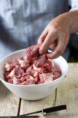 Selective focus. Chef's hands are preparing meat kebab with onions. A bowl of raw meat and a bowl of onions. Barbecue cooking.