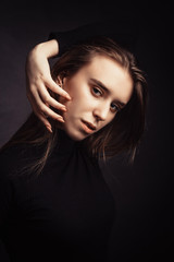 Studio portrait of a young girl with long hair on black background.