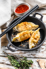 Fried Japanese gyoza dumplings in a pan. White wooden background. Top view
