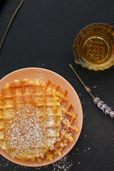 waffles in powdered sugar on a dark background, close-up