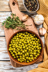 Canned green peas in a wooden bowl. Canned food. White background. Top view