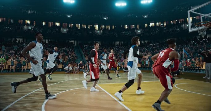 Basketball player scores a goal on a professional basketball stadium. Stadium is made in 3d with animated crowd. Dynamic shot.