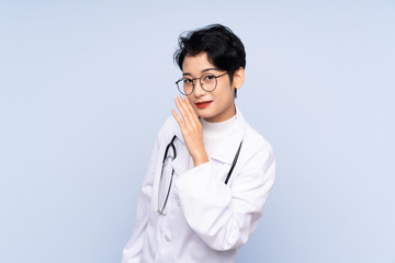 Fototapeta premium Doctor Asian woman over isolated blue background whispering something