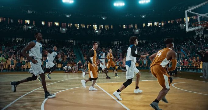 Basketball player scores a goal on a professional basketball stadium. Stadium is made in 3d with animated crowd. Dynamic shot.