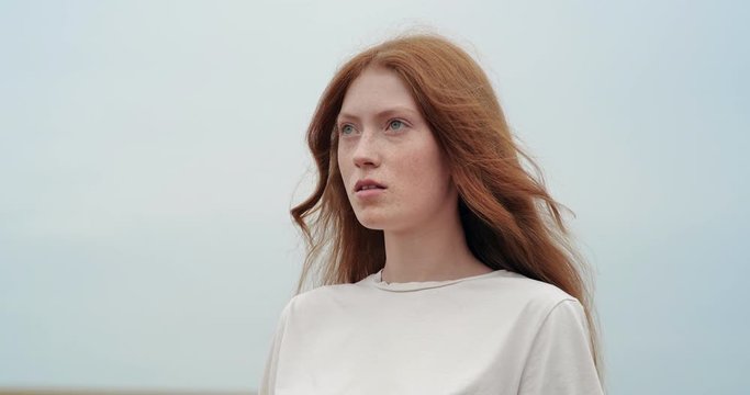 Beautiful Woman Ginger opening her Eyes while looking at Nature, having long nice Eyelashes. Attractive girl with nice Freckles on her Beautiful Face. Red-haired woman with walking on gold Field.
